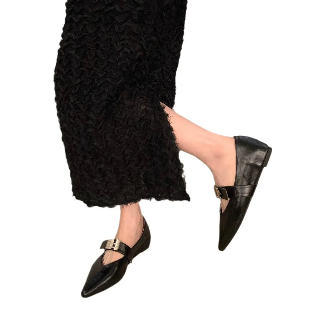 Women's black pointed toe Mary Jane shoes with a silver buckle on a low flat heel.