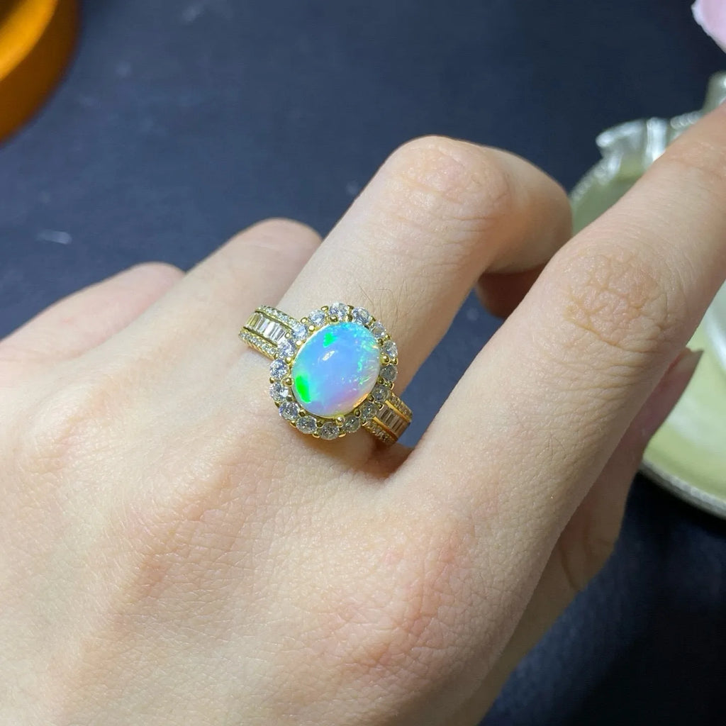 Adjustable opening opal ring in sterling silver with gold tone plating on a model's hand