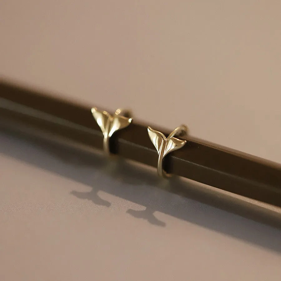 A pair of smooth sterling silver fishtail hoop earrings with a gold plated finish.