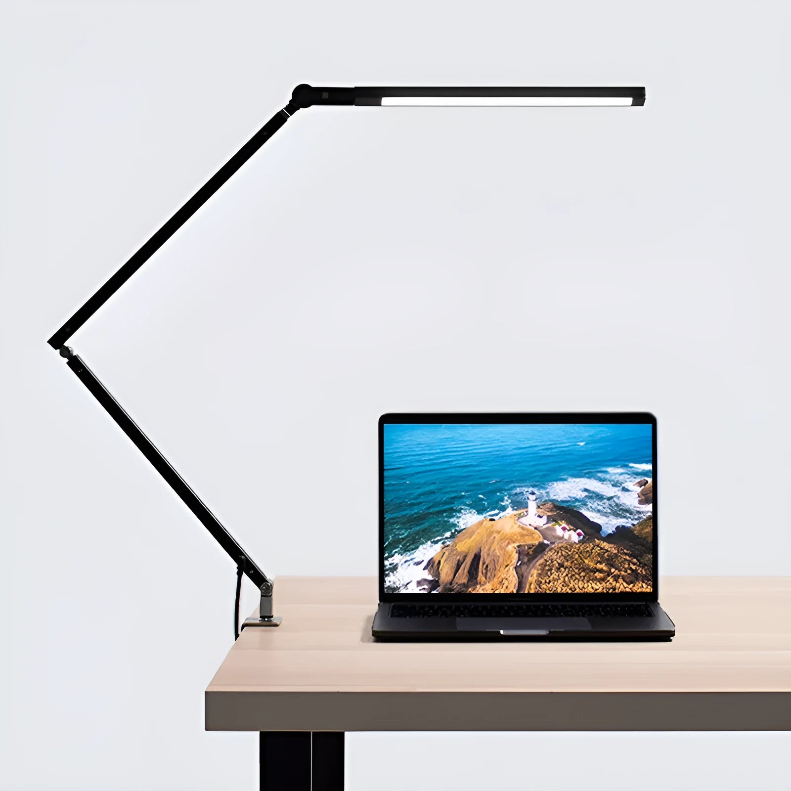 Aluminium clip-on desk lamp with adjustable arm and remote control on a wooden desk.
