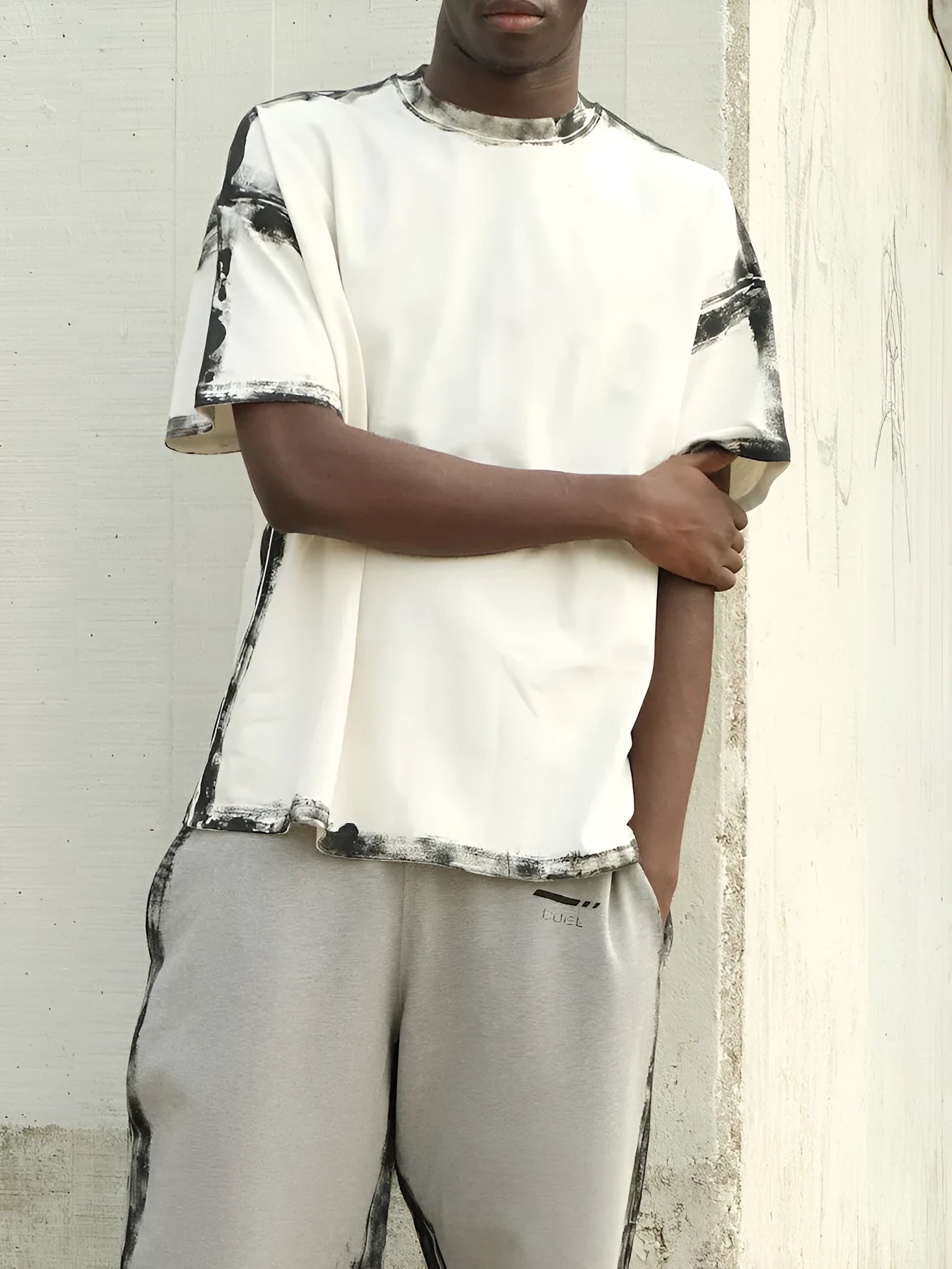 White casual short sleeve top with draped design and printed pattern, laid flat.