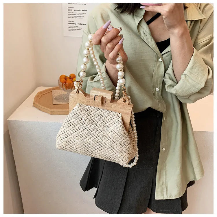 Women's woven straw shoulder bag with pearl chain strap showing interior organisation compartments