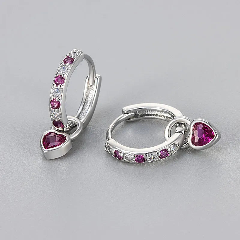 Close-up of women's fashion clip-on earrings with a heart-shaped pink cubic zirconia stone in a gold-coloured copper setting.