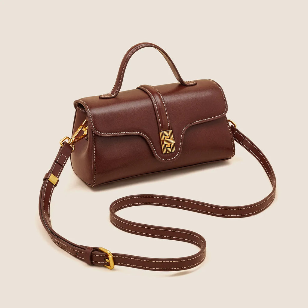 Brown Cambridge-style crossbody messenger bag with clamshell opening and lock detail on a table.