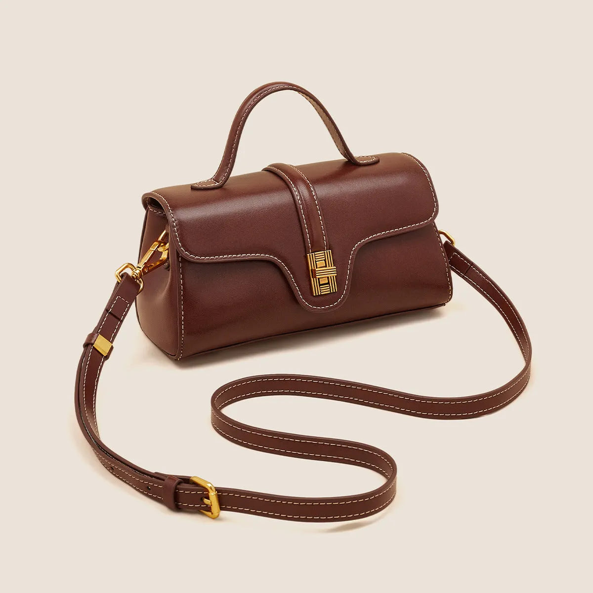 Brown Cambridge-style crossbody messenger bag with clamshell opening and lock detail on a table.
