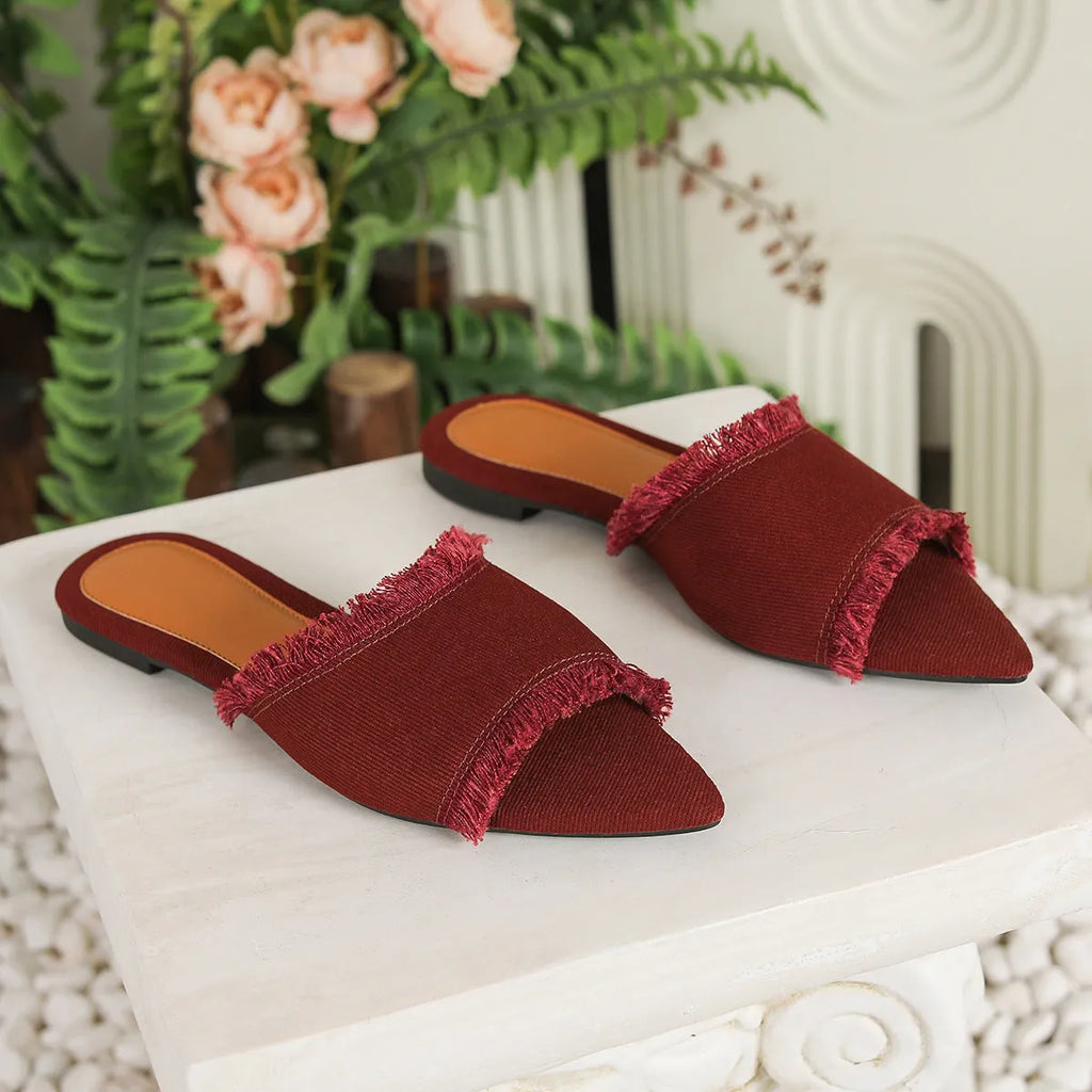 Women's apricot denim flat slippers with a tassel on the front, showing leather lining and lightweight PVC sole.