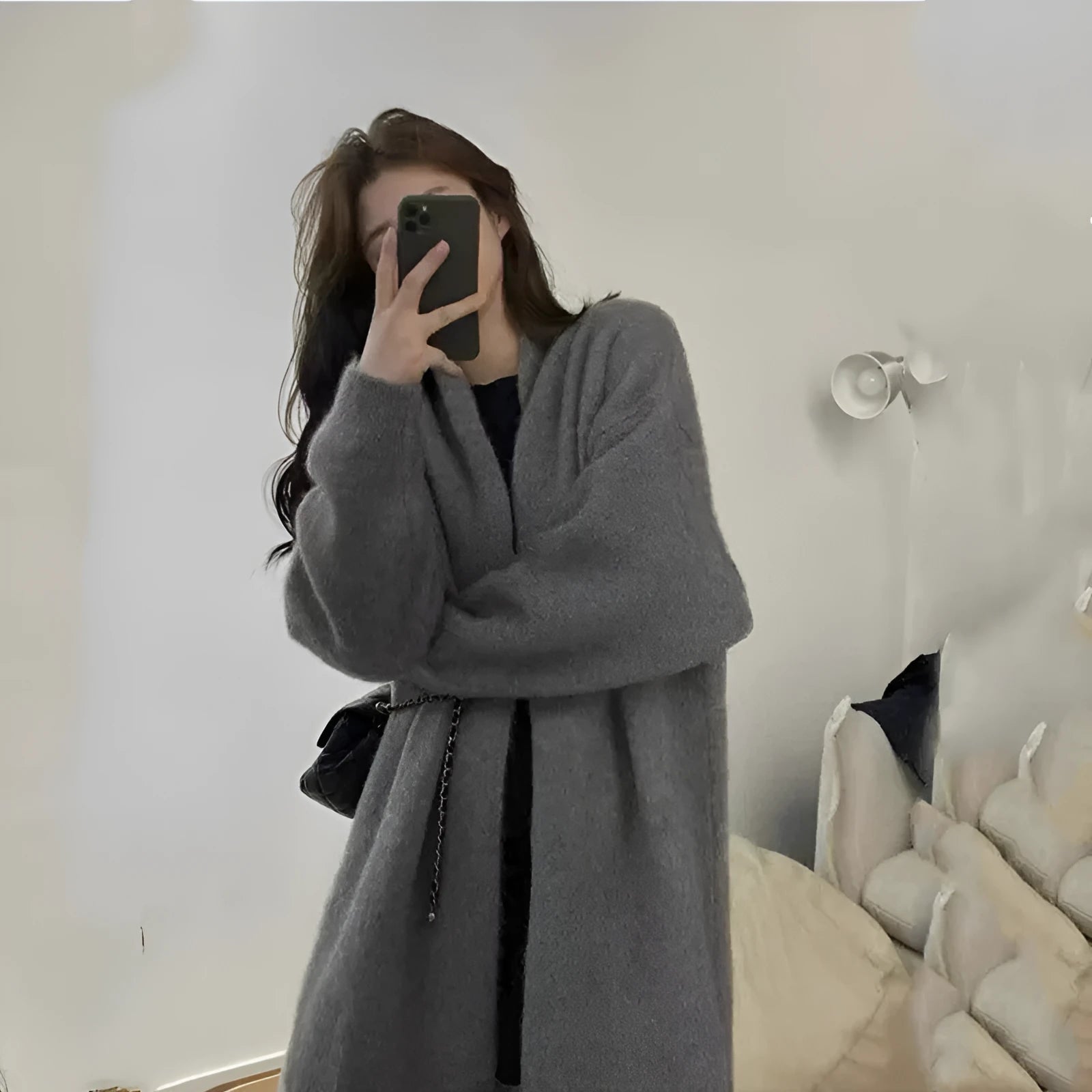 Woman wearing a loose, thick dark gray knitted cardigan with a 3D pattern and long sleeves.