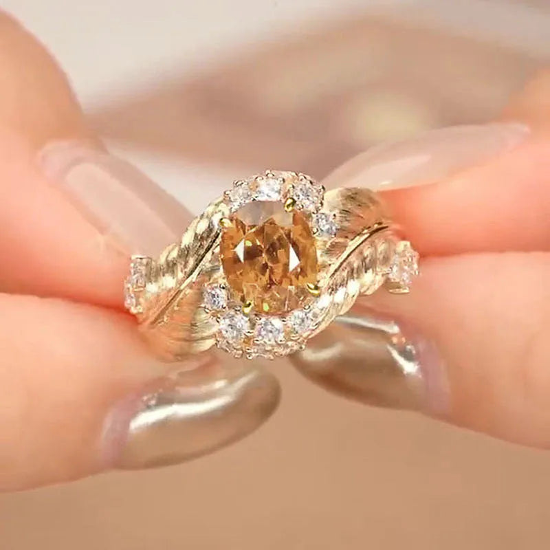 Gold-coloured copper ring with embossed feather design and inlaid yellow zircon stones.