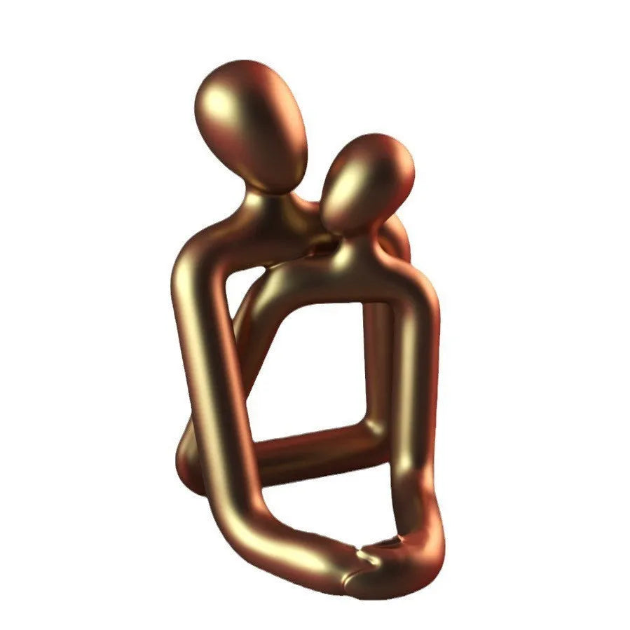 Modern resin sculpture of an embracing couple in milky white or gold finish on a wooden surface.