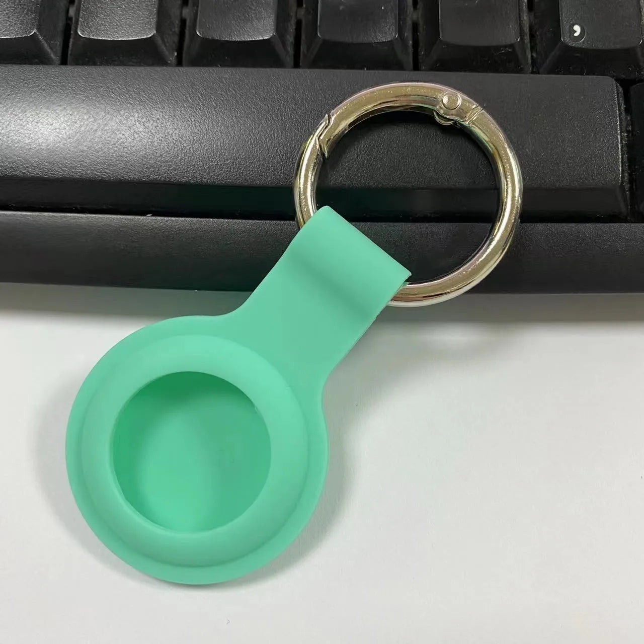 Silicone protective case for Apple AirTag with metal snap button in assorted colours on a keyring.